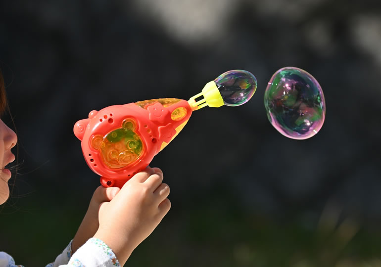 バブルガンでシャボン玉を作って遊ぶ子供