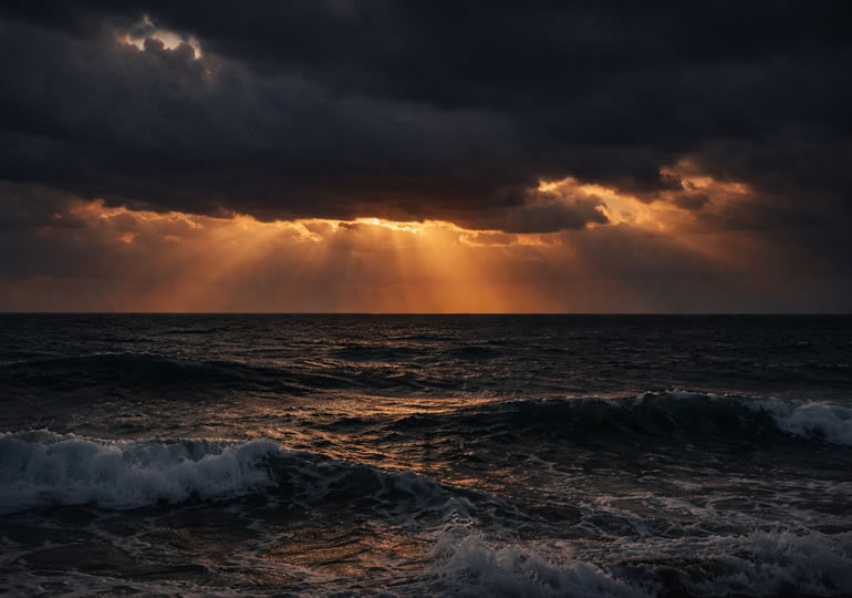 曇り空で夕日が見えない海の様子